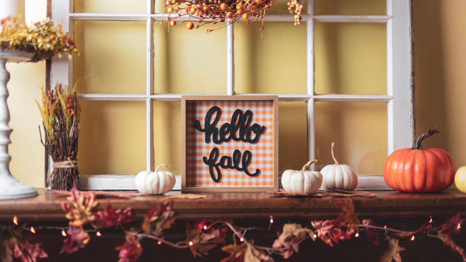 hello fall sign sitting on top of a table around fall decorations